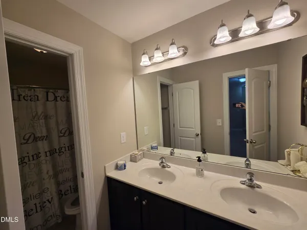 a bathroom with double vanity sinks a toilet a shower a vanity and a mirror