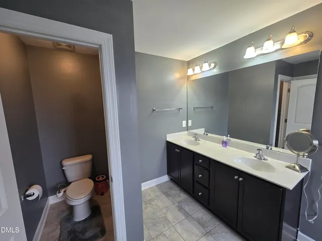 a bathroom with a double vanity sink toilet and mirror