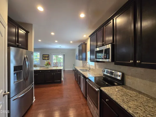 a kitchen with stainless steel appliances granite countertop a refrigerator a stove top oven and sink