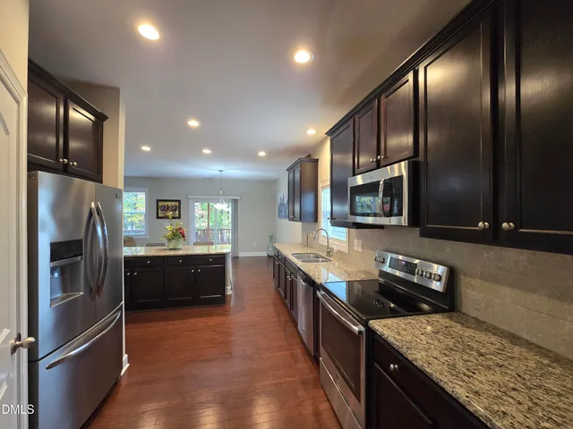 a kitchen with stainless steel appliances granite countertop a refrigerator a stove top oven and sink