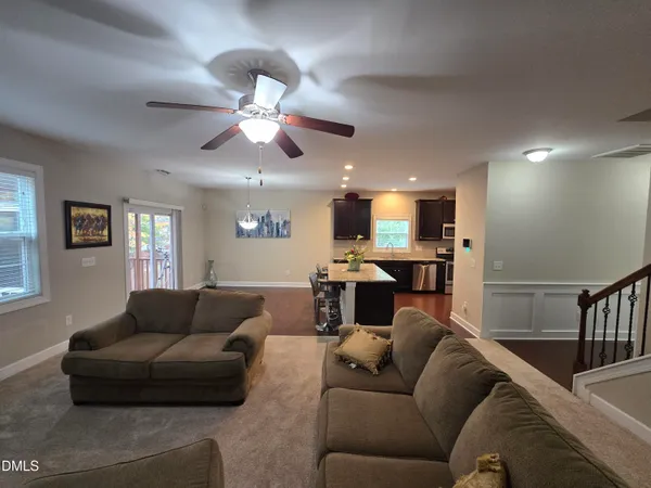 a living room with furniture kitchen view and a chandelier