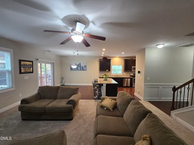a living room with furniture kitchen view and a chandelier