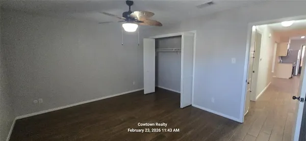 an empty room with wooden floor fan and windows