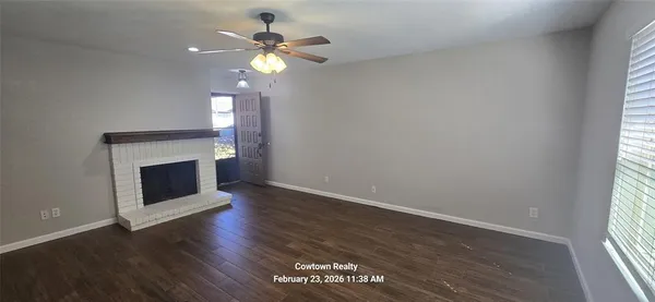 an empty room with wooden floor a chandelier fan and a fireplace