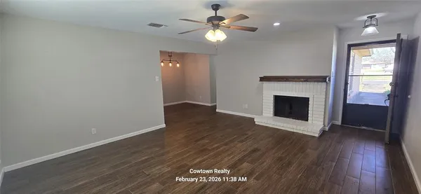 a view of an empty room with wooden floor and a fireplace
