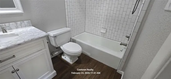 a bathroom with a granite countertop toilet and a bathtub