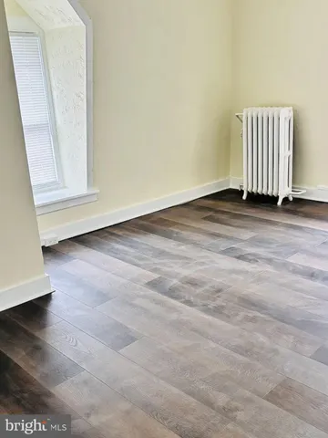an empty room with wooden floor and window