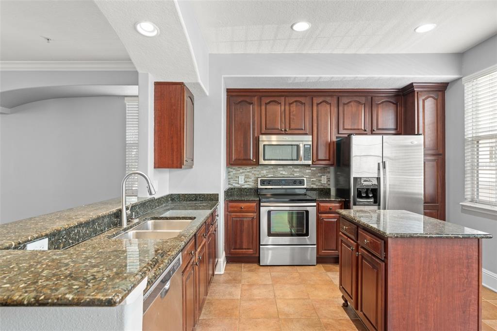 1563 Common Way Road Orlando, FL 32814 - Photo 32 of 47 a kitchen with stainless steel appliances granite countertop a sink stove and refrigerator