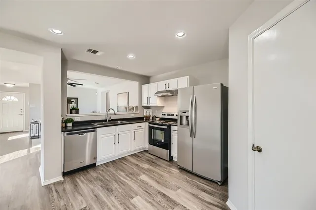 a kitchen with granite countertop a refrigerator stove top oven and sink