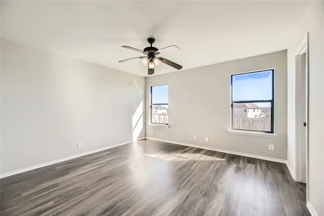 a view of an empty room with a window and wooden floor