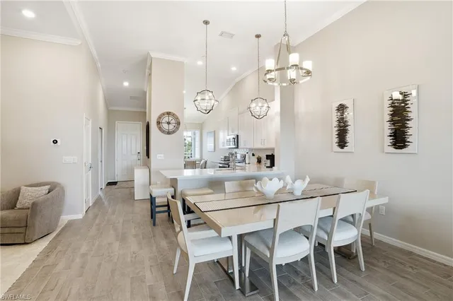 a dining room with wooden floor a chandelier a wooden table and chairs