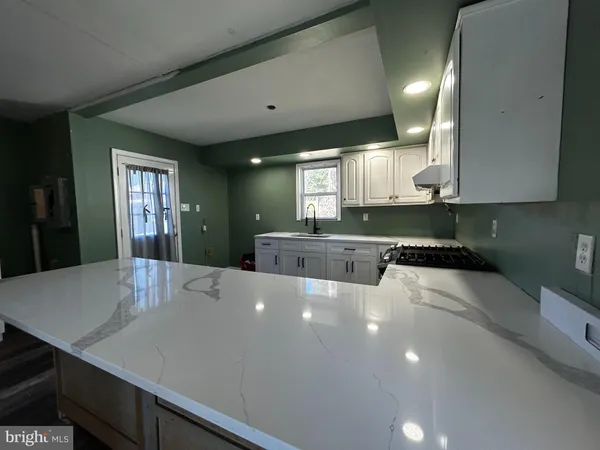a large kitchen with stainless steel appliances a large counter top a stove a chimney a sink and a refrigerator