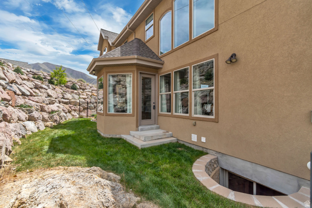 2543 East 700 South Springville, UT 84663 - Photo 6 of 73 View of exterior entry with stucco siding, a lawn, roof with shingles, and a mountain view