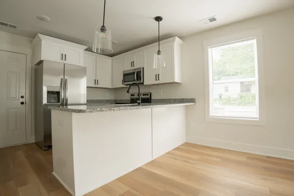 a kitchen with kitchen island white cabinets a sink a center island and stainless steel appliances