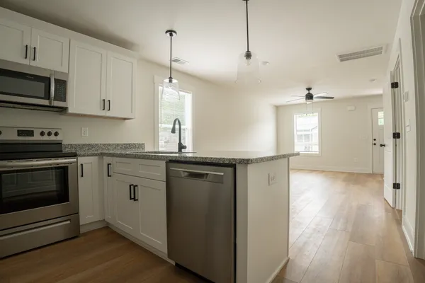 a kitchen with stainless steel appliances granite countertop a refrigerator a stove a sink and white cabinets