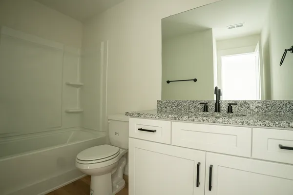 a bathroom with a granite countertop toilet sink and mirror