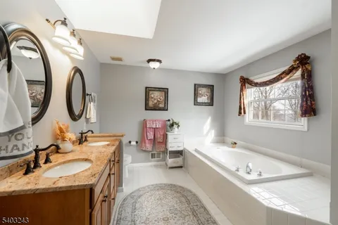 a bathroom with a tub double vanity sink and a mirror