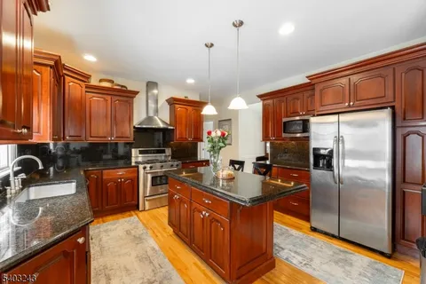 a large kitchen with stainless steel appliances granite countertop a stove a sink dishwasher a refrigerator and a microwave