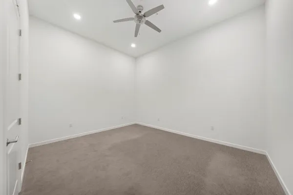an empty room with a ceiling fan and carpet