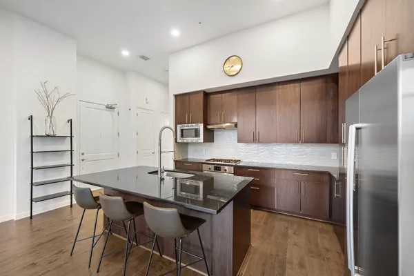 a kitchen with stainless steel appliances granite countertop a kitchen island a stove and a refrigerator