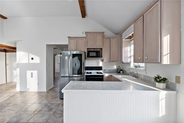 a kitchen with stainless steel appliances granite countertop a stove and a refrigerator with white cabinets