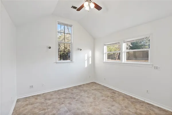 an empty room with windows and fan