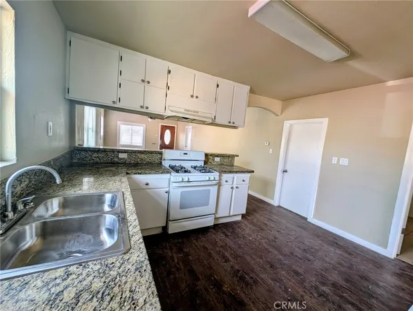a kitchen with granite countertop white cabinets and white appliances