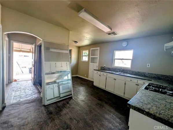 a kitchen with granite countertop a stove a sink and a refrigerator