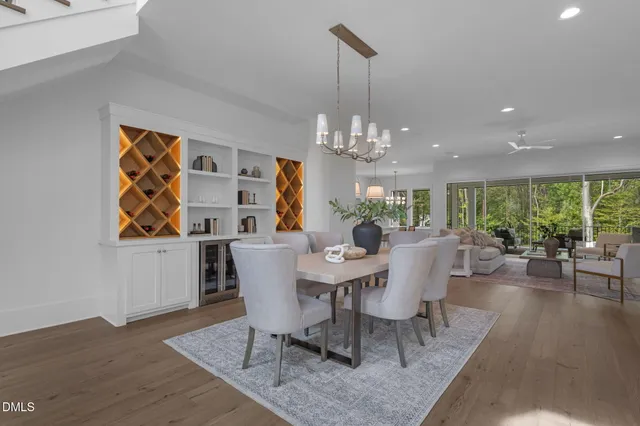 a kitchen with stainless steel appliances granite countertop a stove a sink a microwave a dining table and chairs with wooden floor