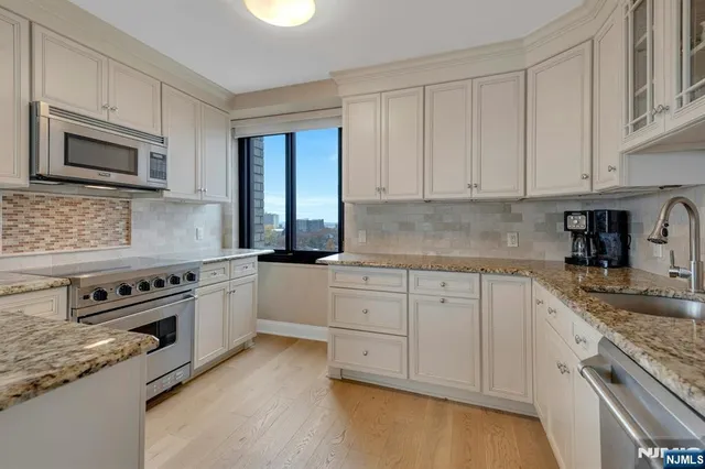 a kitchen with granite countertop white cabinets and stainless steel appliances