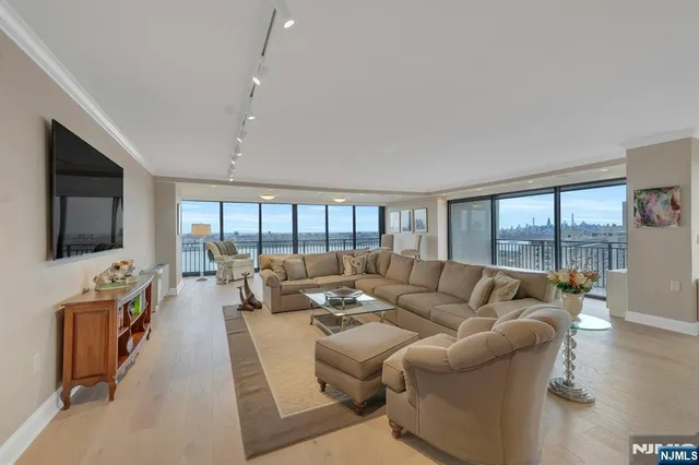 a living room with furniture floor to ceiling window hardwood floor and a flat screen tv