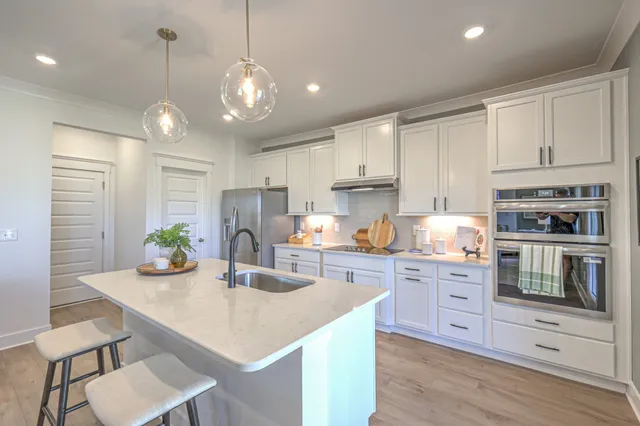 a kitchen with stainless steel appliances kitchen island granite countertop a sink a stove a dining table and chairs