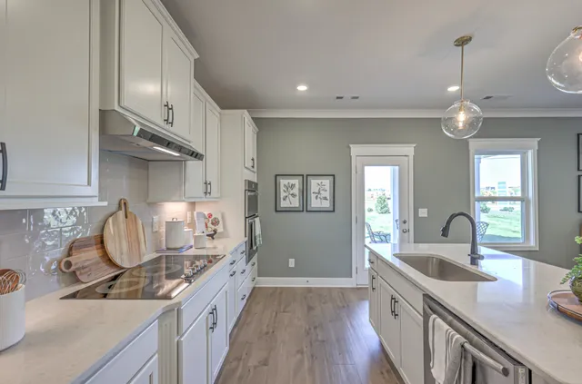a large kitchen with a sink and dishwasher a stove with wooden floors