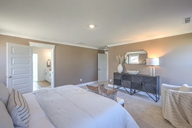 a bedroom with a bed lamps and table chair