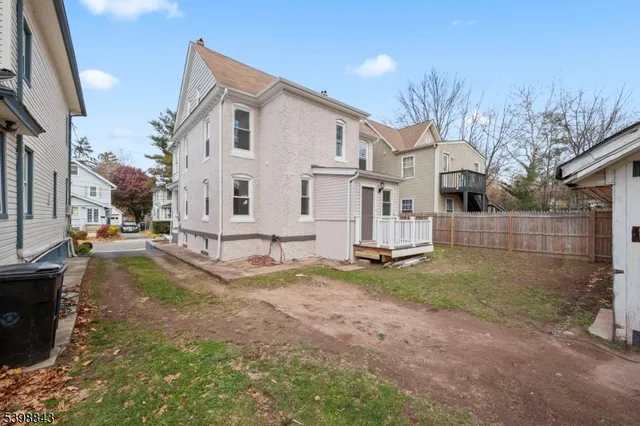 a view of a white house next to a yard with big trees
