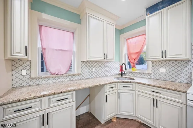 a kitchen with granite countertop white cabinets white appliances and a sink