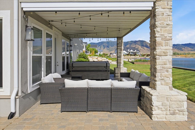 21 Pier Place Tooele, UT 84074 - Photo 91 of 112 Covered patio featuring a paver stone surface, stone-clad support columns, string lighting, and multiple exterior doors