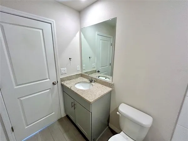 a bathroom with a granite countertop sink toilet and mirror