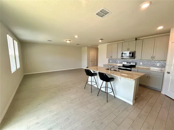 a kitchen with kitchen island granite countertop a stove a sink a microwave and a refrigerator