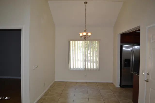 a view of an empty room with window and chandelier fan