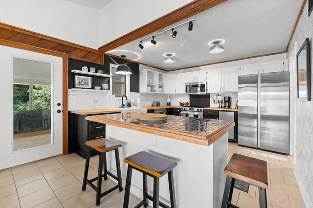 a kitchen with kitchen island a stove a refrigerator and a dining table with wooden floor