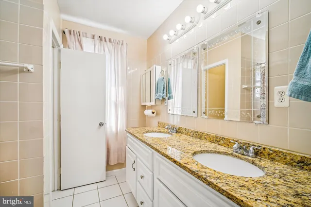 a bathroom with a granite countertop double vanity sink and a mirror