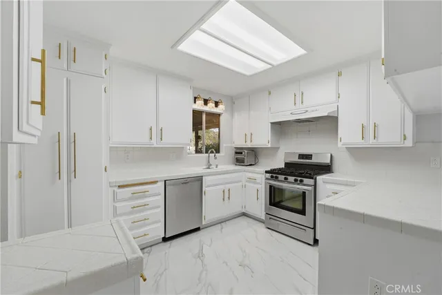 a view of kitchen with granite countertop white cabinets and stainless steel appliances