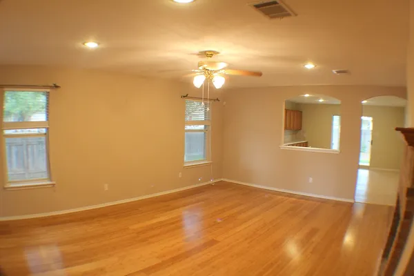 a view of empty room with wooden floor and fan