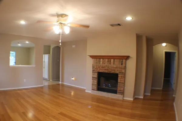 a view of an empty room with wooden floor and a fireplace