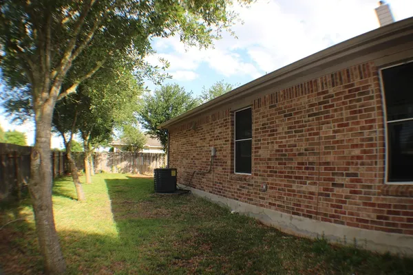 a brick house with a yard and a large tree