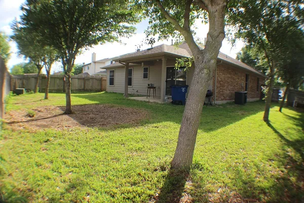 a view of a house with backyard and trees
