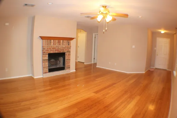 a view of an empty room with a fireplace and a fan