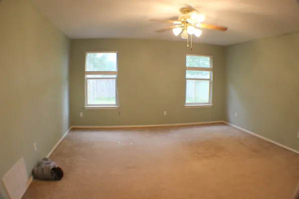 an empty room with windows and chandelier fan