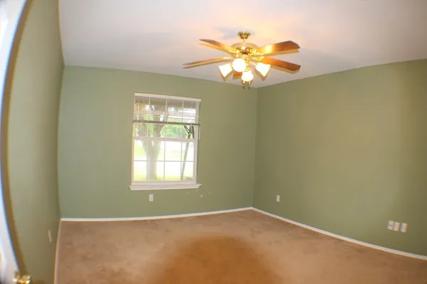 an empty room with windows and chandelier fan